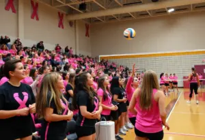 Fans wearing black and pink attire supporting UNC Asheville Volleyball during a match.